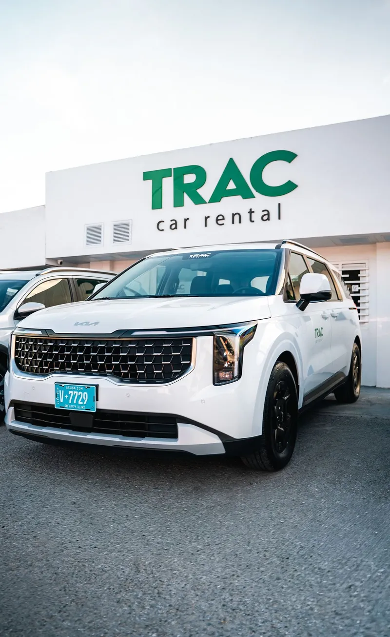TRAC's white Kia Carnival in front of the TRAC Car Rental office